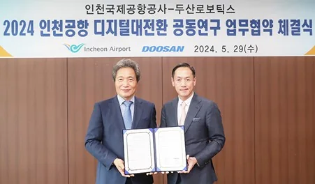 두산로보틱스와 인천국제공항공사가 디지털 전환 업무협약서를 들고 있는 모습